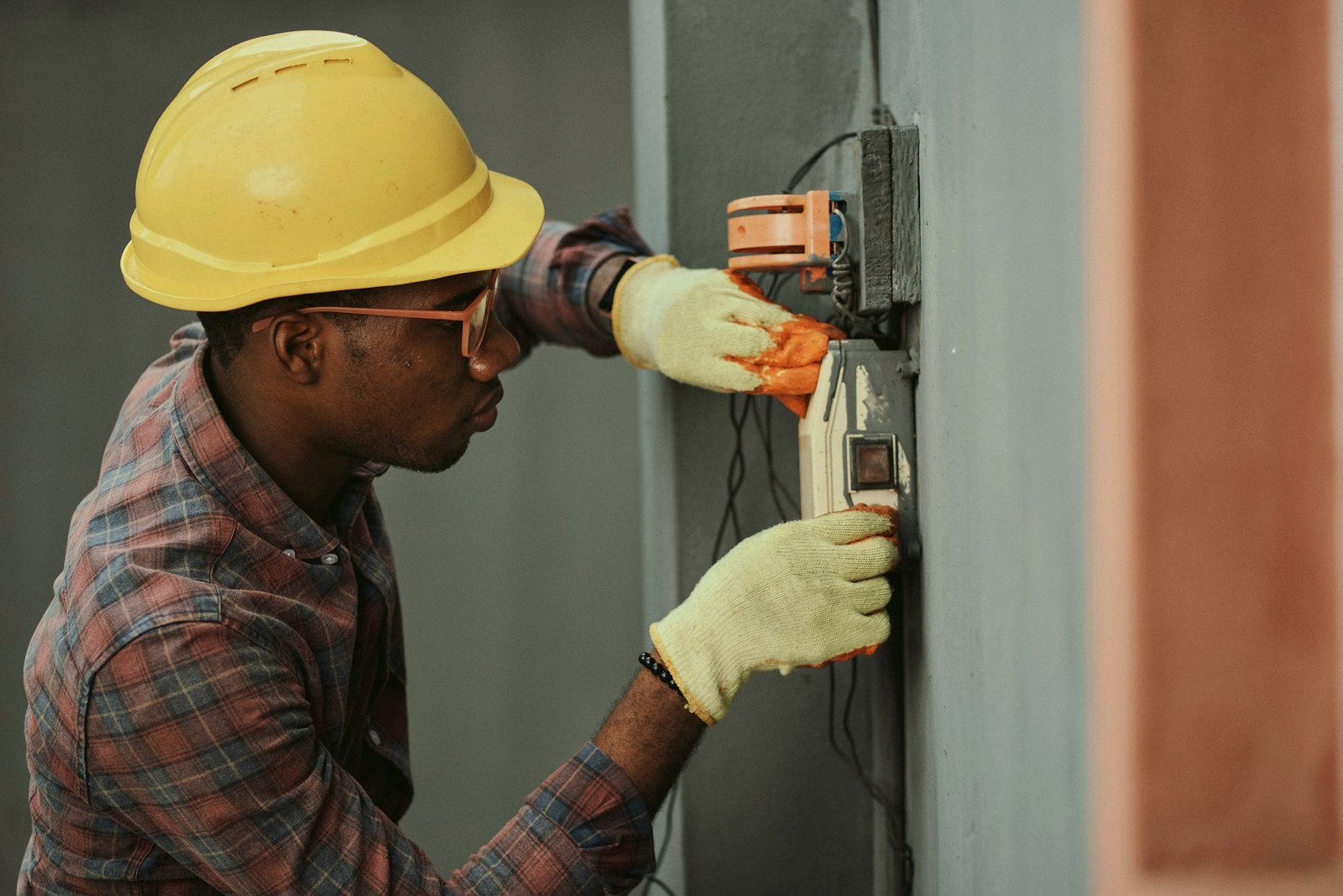 An electrician working on a panel with both hands busy — while cheaply answers his phone